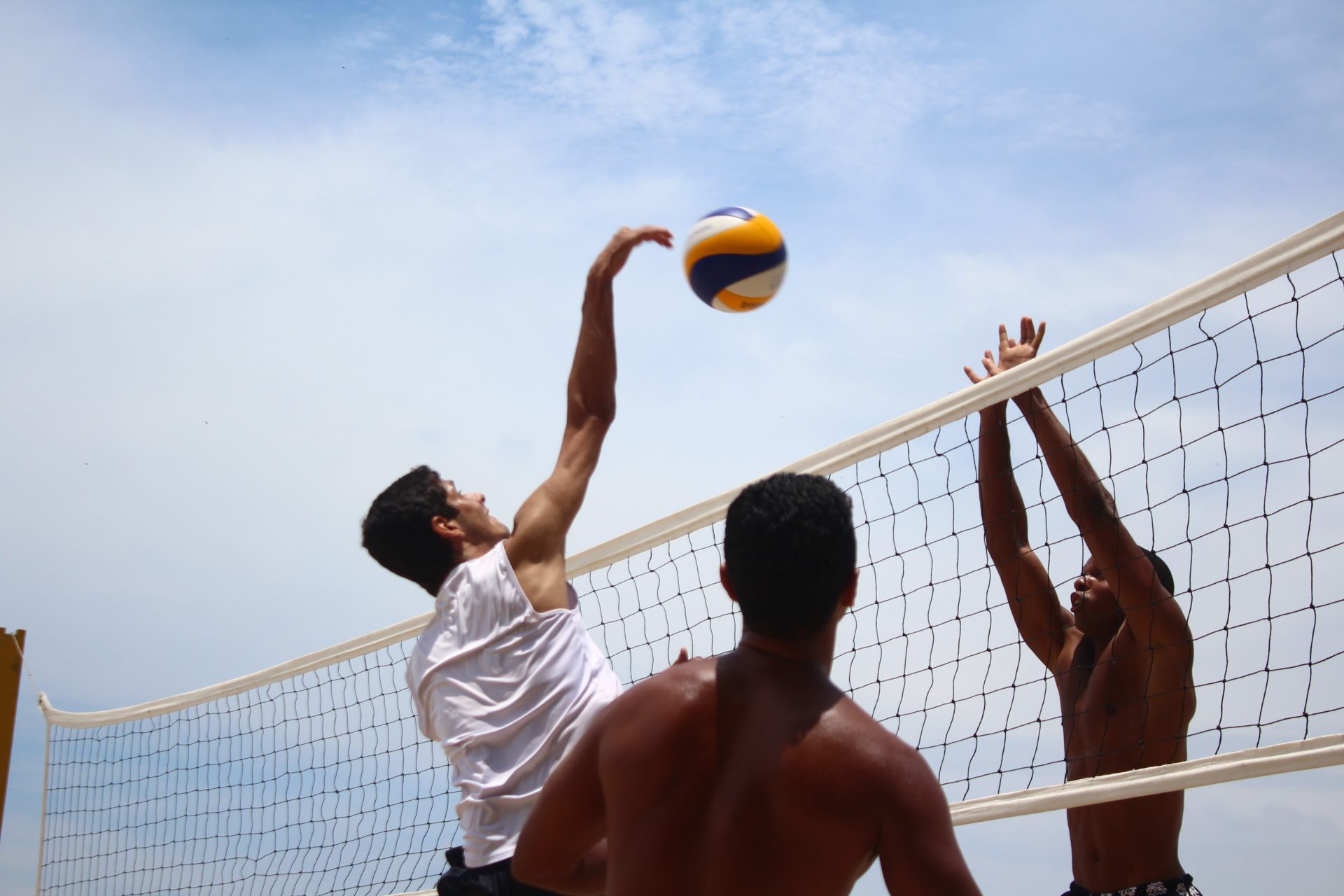 Imagem de pessoas jogando vôlei na praia.